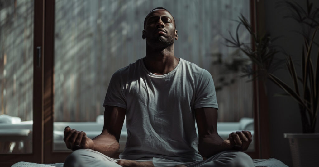 Man sitting cross-legged in meditation pose with closed eyes and calm lighting